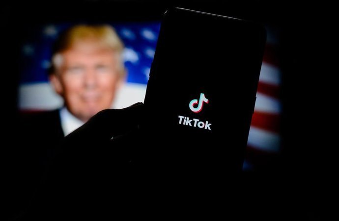 Archivo - Composici&oacute;n de imagen con el logotipo de TikTok en un tel&eacute;fono m&oacute;vil con una bandera estadounidense y un retrato del presidente de EEUU, Donald Trump, de fondo