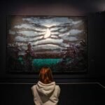 Un visitante se encuentra junto a las obras de arte del artista ingl&eacute;s David Hockney