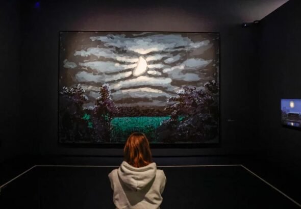 Un visitante se encuentra junto a las obras de arte del artista ingl&eacute;s David Hockney