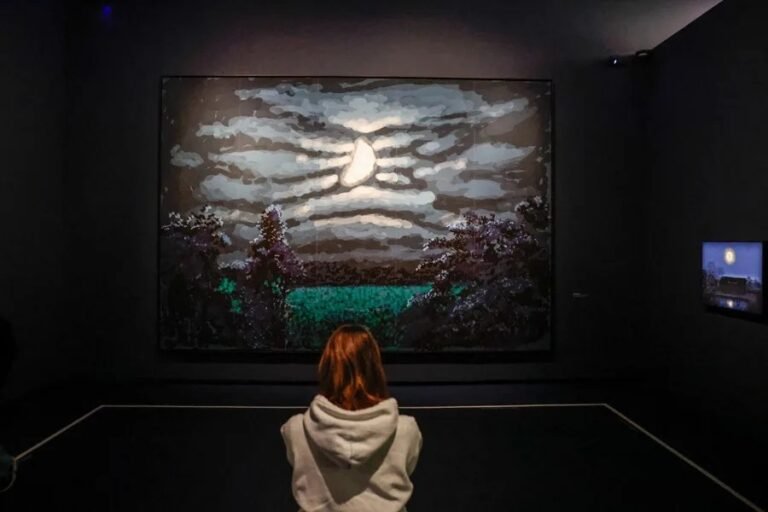 Un visitante se encuentra junto a las obras de arte del artista ingl&eacute;s David Hockney